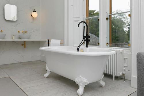 a white bath tub in a bathroom with two sinks at Lews Castle in Stornoway