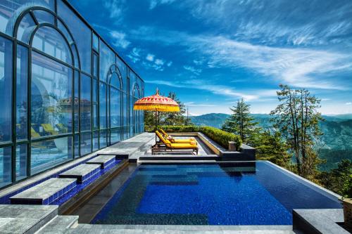 a house with a pool and an umbrella at Wildflower Hall, An Oberoi Resort, Shimla in Shimla