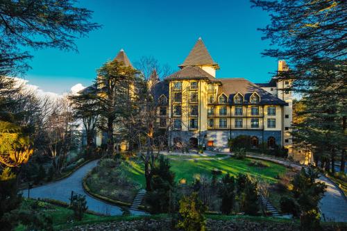 Wildflower Hall, An Oberoi Resort, Shimla في شيملا: منزل كبير أمامه ساحة كبيرة