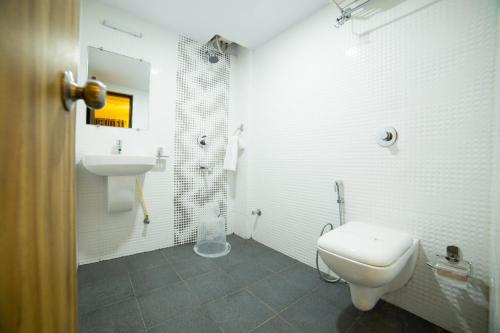 a white bathroom with a toilet and a sink at Hotel Plaza Heights in Bangalore