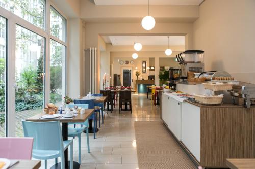 ein Restaurant mit Tischen und Stühlen und eine Küche in der Unterkunft Nu Wave Hotel Berlin in Berlin