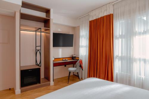 a bedroom with a bed and a desk with a monitor at NAIADES the residence ioannina castle in Ioannina