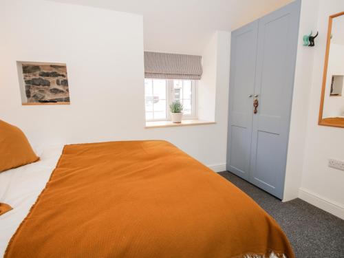 Un dormitorio con una cama con una manta naranja. en Cuddfan, en Llangollen
