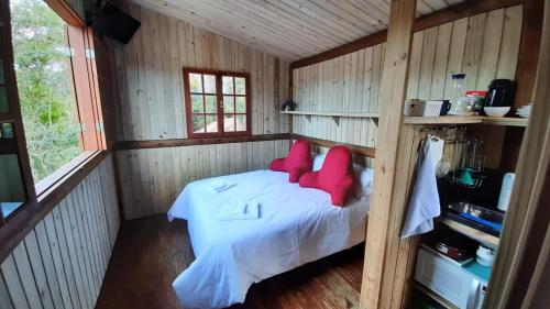 um quarto com uma cama com almofadas vermelhas em Itaipava, Cabana No Alto do Vale em Itaipava