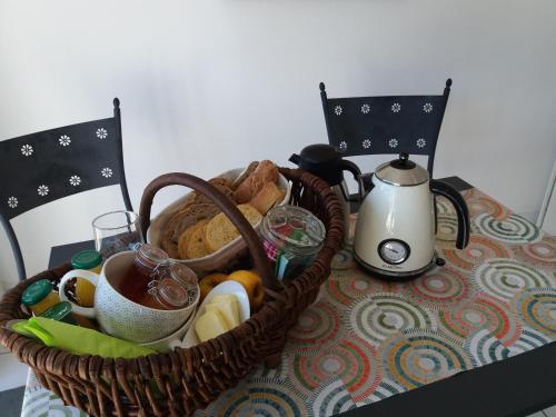 ブレシュイールにあるChambre d'hôtes La Thibaudièreのテーブルの上にはパンの入ったバスケットとティーケトルが置かれている