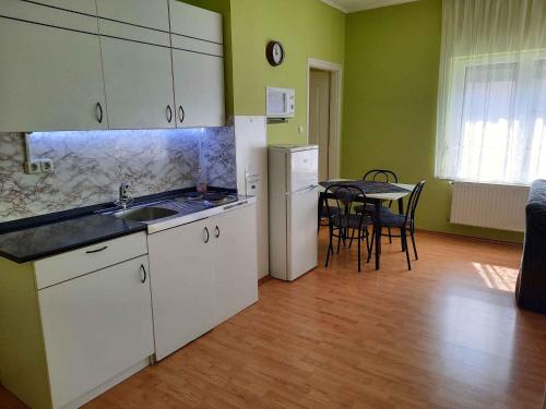una cocina con armarios blancos y una mesa con sillas. en Apartment Siofok, Lake Balaton 5 en Siófok