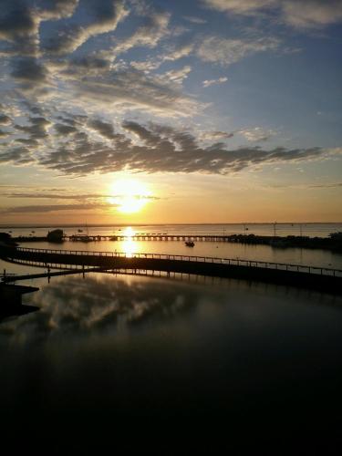 a sunset over the water with a pier at Absolute Waterfront - Tropical Aurora Top Floor Over The Water in Darwin