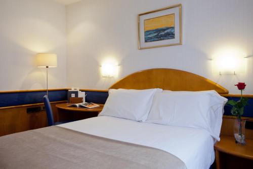 a hotel room with a bed with white sheets and pillows at Agumar in Madrid