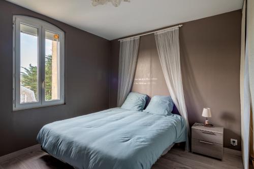 a bedroom with a bed with blue sheets and a window at Appartement près du port centre et plage - Vue mer in Courseulles-sur-Mer