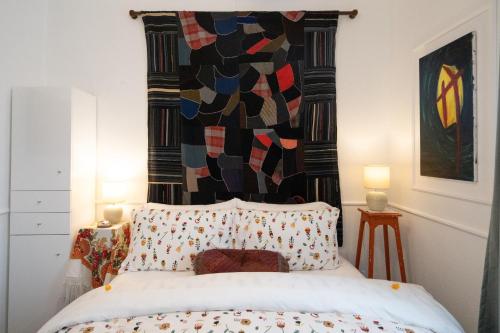 a bedroom with a bed with a colorful quilt on the wall at Quinta Pereirinha Farm - Bed & Breakfast - Pico Island, Azores - Private 3 Bedroom Home on a Working Farm w Ocean Views in São Roque do Pico