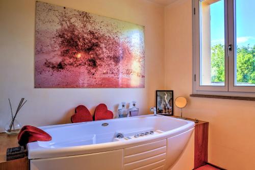 a bath tub in a bathroom with a painting on the wall at Villa Le Cave 12, Emma Villas in La Caduta