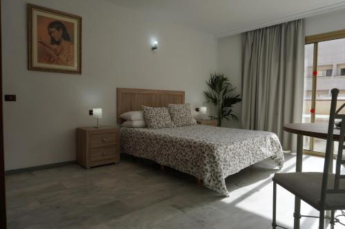 a bedroom with a bed and a table and a window at Apartamentos Pirámides in Playa de las Americas