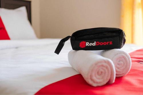 a red book bag on a bed with towels at RedDoorz near Politeknik Negeri Lampung in Lampung