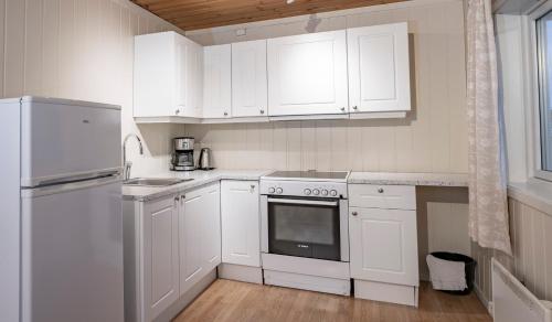 a white kitchen with white cabinets and a refrigerator at Lillehammer Camping in Lillehammer