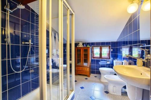 a blue tiled bathroom with a sink and a toilet at Chata Kataryniarza in Karłów