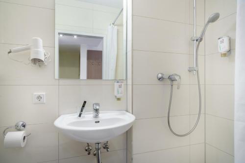 a white bathroom with a sink and a shower at Novum Hotel Norddeutscher Hof Hamburg in Hamburg