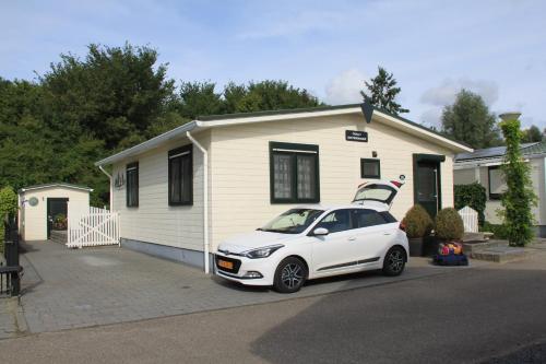 a white car parked in front of a house at Chalet Buutengeweun, met luxe JACUZZI en TONSAUNA in Sint Annaland