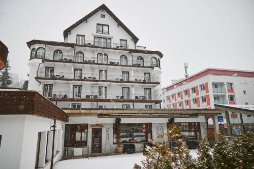 a large white building with snow in front of it at Hotel Meierhof in Davos