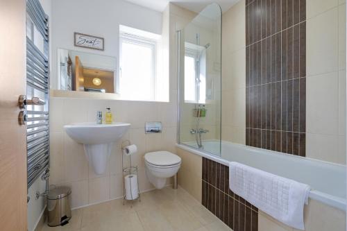 a bathroom with a sink and a toilet and a tub at London Heathrow Living Holywell Serviced Houses - 3 and 4 bedrooms By Ferndale in Stanwell