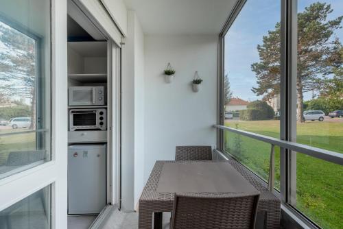 un balcon avec une table, des chaises et une fenêtre dans l'établissement Studio avec loggia - à 200m de la plage - Parking, à Courseulles-sur-Mer