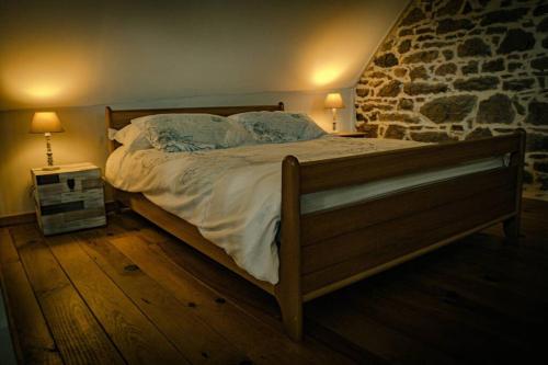 a bed in a bedroom with a stone wall at Les Gîtes du Gouélou in Callac