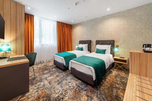 a hotel room with two beds and a desk at Tomis Garden Aparthotel Bucuresti in Bucharest