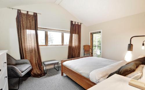 a bedroom with a bed and a chair and a window at Chalets Alpins- 19 Chemin Alpin in Stoneham