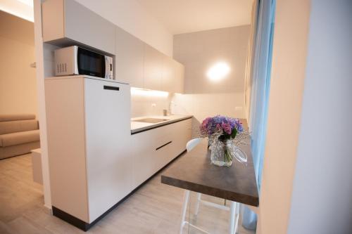 a white kitchen with a table with a vase of flowers at Marigold Residence in Roseto degli Abruzzi