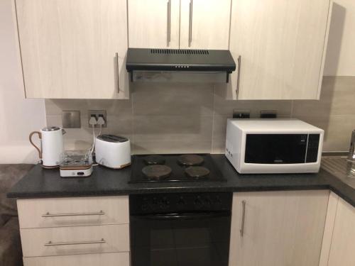 uma cozinha com um micro-ondas e um fogão forno superior em Luxury Suites at St Petes Duplex Townhouse em Newton Park