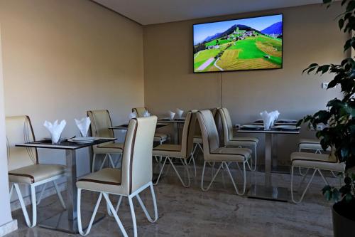 uma sala de jantar com mesas e cadeiras e uma televisão de ecrã plano em Hotel Residence Imiplage em Agadir
