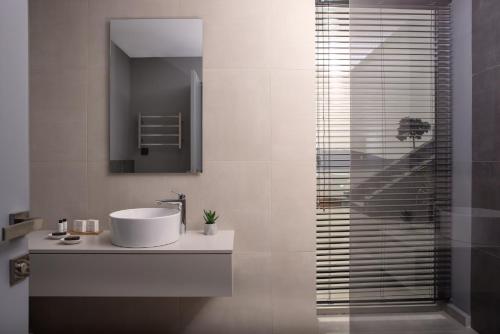 a bathroom with a sink and a glass shower at Rock Bay Villas - Luxury Villas in Crete in Agia Pelagia