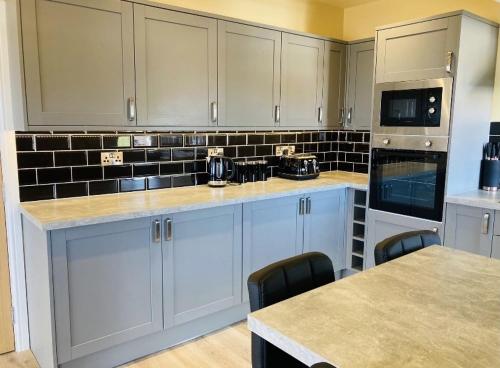 a kitchen with white cabinets and black tile on the wall at Marine Boathouse View Apartment in Skegness