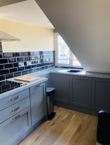 a kitchen with gray cabinets and a sink and a window at Marine Boathouse View Apartment in Skegness
