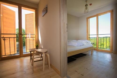 a bedroom with a bed and some windows and a chair at Illaberek Vendégház in Sukoró