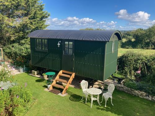 a green tiny house with a table and chairs at Corner House in Cudworth