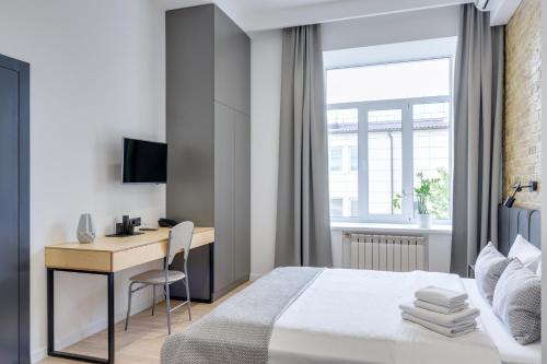 a bedroom with a bed and a desk and a window at Centrooms Kropivnizkogo Mini-Hotel in Kyiv