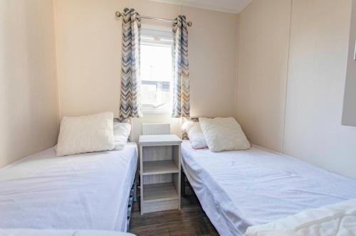 two twin beds in a room with a window at Chalet 536 op Recreatiepark De Wielen in Sint Maarten