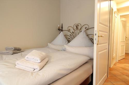 ein Schlafzimmer mit einem weißen Bett und Handtüchern darauf in der Unterkunft Haus am Park Wohnung Nr3 in Spiekeroog