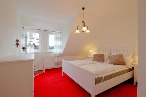een slaapkamer met een wit bed en een rode loper bij MU32a Dachgeschoss in Dorum Neufeld
