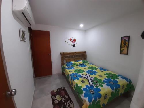 a bedroom with a bed with a floral bedspread at Hostal Casa Mathias in Cartagena de Indias