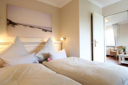 1 dormitorio con 2 camas y almohadas blancas en Haus am Park Wohnung Nr6 en Spiekeroog