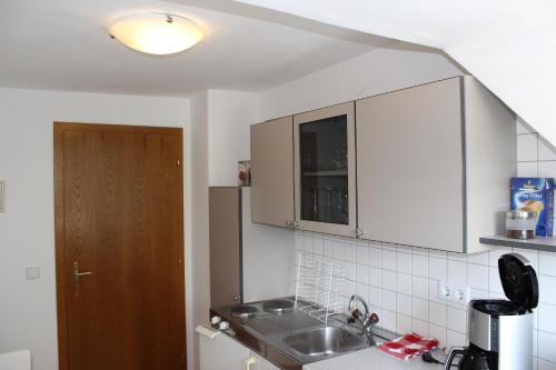 una cocina con armarios blancos y fregadero en Ferienwohnung und Gästezimmer Korb, en Krumpendorf am Wörthersee