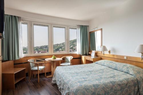 une chambre d'hôtel avec un lit, une table et des chaises dans l'établissement Hotel Budapest, à Budapest