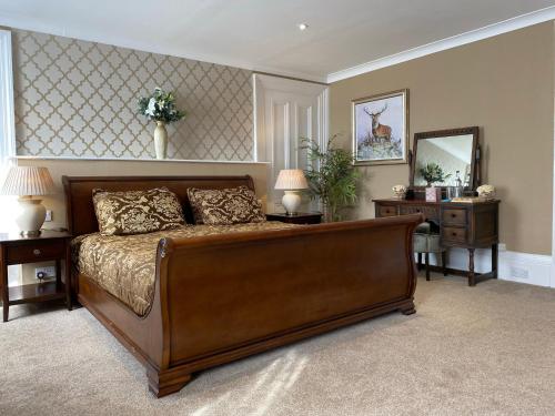 a bedroom with a large bed with two tables and a mirror at Ernespie House Hotel in Castle Douglas