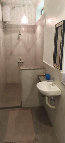 a bathroom with a sink and a shower with a mirror at Isai Ambalam guest house in Puducherry