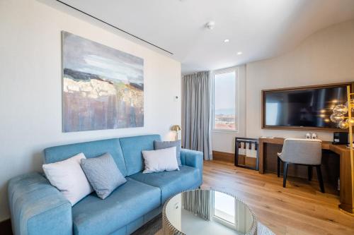 a living room with a blue couch and a tv at Soho Boutique Equitativa in Málaga