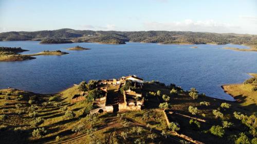 a house on a hill next to a body of water at Herdade Monte da Tapada in Alqueva