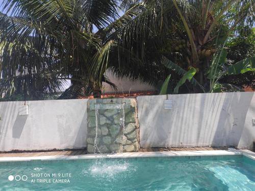 a pool with a fence and a palm tree at Casa Souza in Ilhéus