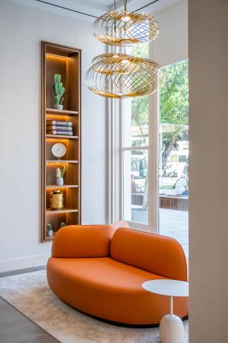 an orange couch in a living room with a chandelier at Soho Boutique Equitativa in Málaga