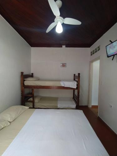 a bedroom with two beds and a ceiling fan at Pousada Recanto da Praia in Bertioga